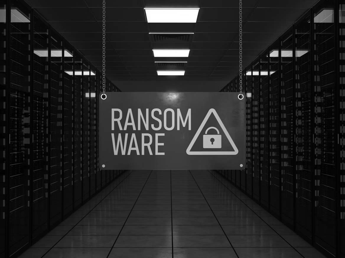 A sign reading RANSOMWARE with a lock icon hangs in a Portland server room filled with rows of servers lit by red lights, conveying the looming threat of ransomware attacks.