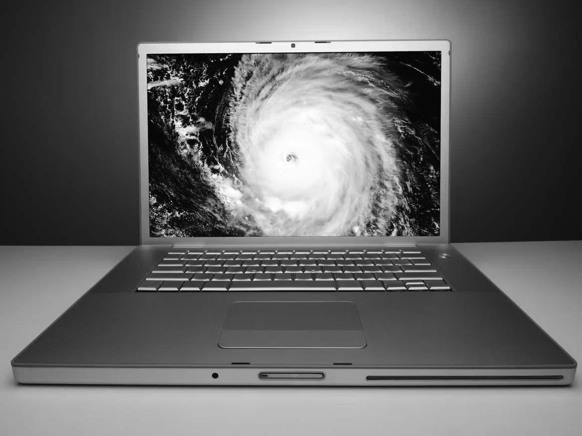 A silver laptop on a white surface displays a satellite image of a hurricane with a visible eye on its screen, highlighting the risk of data disaster for any small business, set against a blue gradient background.