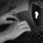 Hands typing on a laptop keyboard with a digital graphic of a shield and padlock symbol, representing cybersecurity, data protection, and overcoming compliance obstacles.